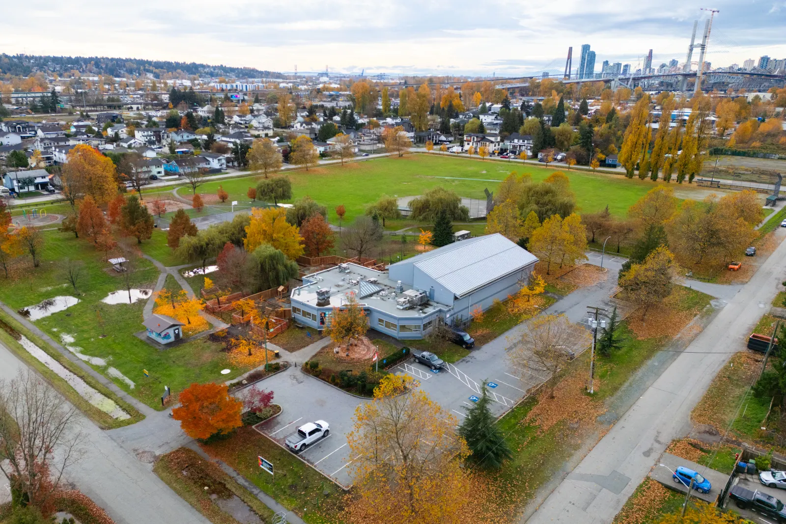 Aerial view of the Bridgeview community centre in Surrey, with its gym and single-storey wing set among autumn trees, parking and a park